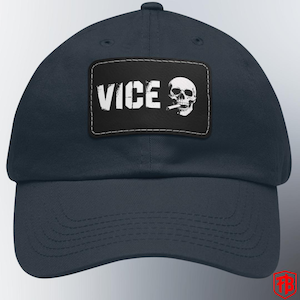 May include: Navy blue baseball cap with a rectangular patch featuring the word "VICE" in white block letters and a white skull smoking a cigarette. The cap has a curved brim and a stitched design.