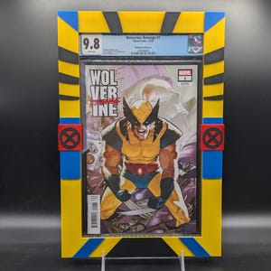 Puede incluir: Un cómic calificado en una caja protectora amarilla, azul y negra. La portada del cómic presenta a Wolverine con un traje amarillo y negro, con el título "Wolverine: Revenge #1" y una calificación de 9,8.