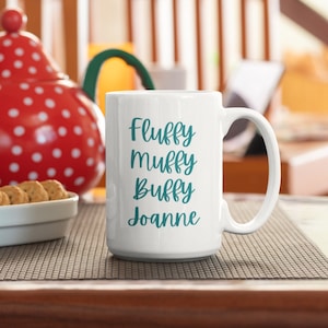 May include: White ceramic mug with a teal design that reads "Fluffy Muffy Buffy Joanne".