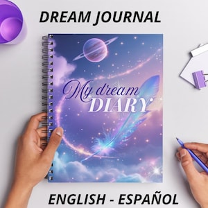 Puede incluir: Un cuaderno espiral morado y azul con un diseño de galaxia. La portada presenta una pluma, un planeta y estrellas. El texto "My dream DIARY" está escrito en letra cursiva. El cuaderno está etiquetado como "DREAM JOURNAL" y "ENGLISH - ESPAÑOL".