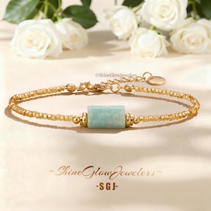 May include: A gold-toned bracelet featuring a central rectangular light green stone bead flanked by small gold beads and a chain of tiny gold-colored beads. The bracelet includes a lobster clasp, an extender chain, and a small round tag with ShineGlowJewelers.