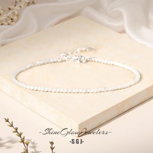 May include: A delicate white gemstone bracelet with a silver clasp. The bracelet is made of small, round beads and is perfect for everyday wear.