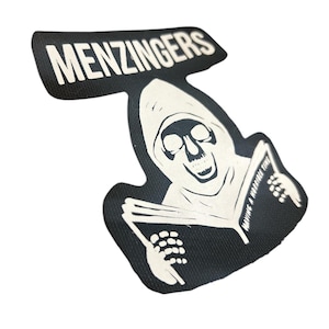 May include: Black and white iron-on patch featuring a skeleton in a hooded robe reading a book with the text "Having a horrible time" on the book. The text "MENZINGERS" is at the top of the patch.