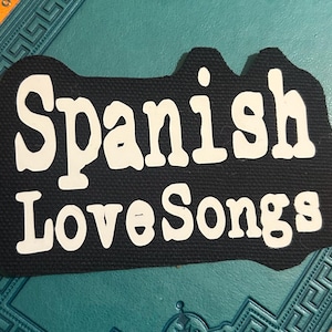 May include: Black fabric patch with white text that reads "Spanish Love Songs".