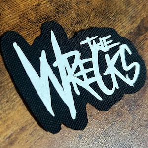 May include: Black fabric patch with white lettering that reads "The Wrecks".