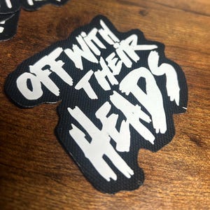 May include: Black and white sticker with the text "Off With Their Heads" in a bold, stylized font.