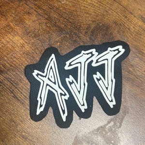 May include: A black patch with the word "ATT" written in white, stylized lettering.