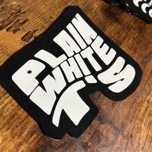 Puede incluir: Un parche de tela negro con las palabras "PLAIN WHITE T's" en blanco, con letras estilizadas.