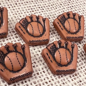 May include: Six brown ceramic buttons shaped like baseball mitts with a baseball inside each mitt.