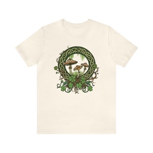 May include: A white t-shirt with a green Celtic knot design featuring three mushrooms and shamrocks.