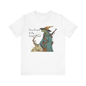 May include: White t-shirt with a green lizard wearing a wizard hat and holding a sword. The text "King Gizzard & the Lizard Wizard" is printed on the shirt.