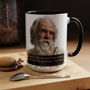 May include: White ceramic mug with a black rim and handle. The mug features a portrait of Socrates and a quote: "There is only one good, knowledge, and one evil, ignorance - Socrates".
