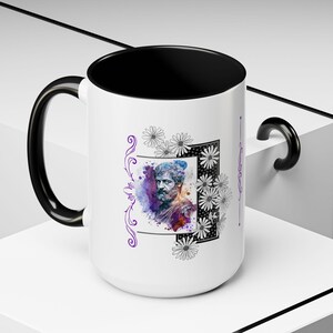 Puede incluir: Taza de cerámica blanca con asa y borde negros. La taza presenta una ilustración de acuarela de un rostro masculino con tonos morados y azules. La ilustración está rodeada de dibujos lineales en blanco y negro de flores.
