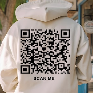 May include: A white hoodie with a black QR code and the text "SCAN ME" printed on the back.