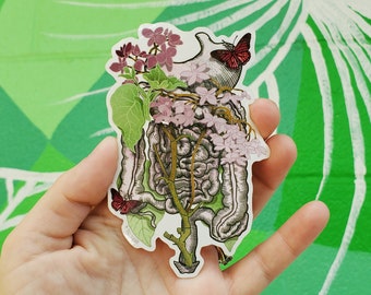 Könnte beinhalten: Ein Aufkleber mit einer detaillierten anatomischen Illustration des menschlichen Verdauungssystems, verziert mit zarten rosa Blüten und zwei roten Schmetterlingen.
