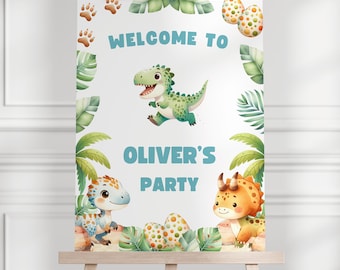 Op de afbeelding: Welkom bij Oliver's Party bord met een groene dinosaurus, een blauwe dinosaurus en een oranje dinosaurus. Het bord heeft een witte achtergrond met groene bladeren en bruine dinosauruspootjes.