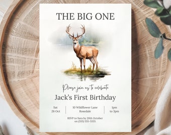 May include: A watercolour illustration of a deer with antlers standing in a lake. The text "The Big One" is at the top of the invitation. The text "Please join us to celebrate Jack's First Birthday" is below the deer. The invitation includes the date, time, and location of the party. The text "RSVP to Sara by 20th October on (555) 555-5555" is at the bottom of the invitation.