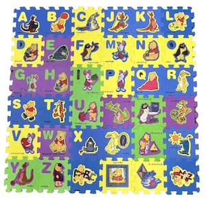 May include: A multi-colored foam alphabet floor mat featuring Winnie the Pooh characters and objects. Each square displays a letter from A to Z, accompanied by a corresponding illustration and word, such as Balloon, Eeyore, Piglet, and Tigger, in a grid.