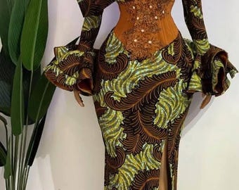 May include: A long-sleeved dress with a brown and green leafy pattern. The dress has a fitted bodice with a sheer overlay and a high neckline. The sleeves have large ruffles at the cuffs. The dress has a slit up the front.