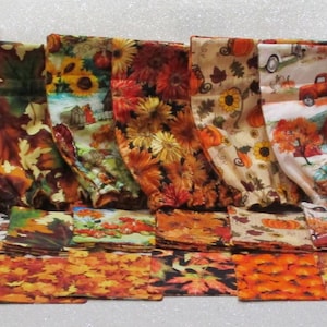 May include: A collection of 18 fabric bags with autumnal designs. The bags feature various patterns, including leaves, pumpkins, turkeys, and other fall-themed imagery. The bags are made of a soft, colorful fabric and are perfect for gift wrapping or storage.