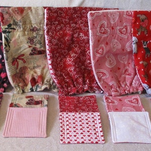 May include: A set of eight handmade fabric bags with a Valentine's Day theme. The bags are made of various fabrics with different patterns, including hearts, flowers, and dogs. The bags are all lined with a white fabric and have a drawstring closure.