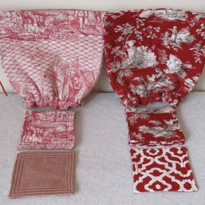 Puede incluir: Dos bolsas de tela roja con cordón de ajuste y patrones blancos, una con un diseño floral y la otra con un diseño geométrico. Cuatro posavasos de tela roja con patrones blancos, dos con diseños florales y dos con diseños geométricos.