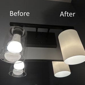 May include: A black, rectangular light fixture with three light sources. The left side shows a clear glass shade with a bright bulb, labeled "Before." The right side shows a white cylindrical shade, labeled "After."