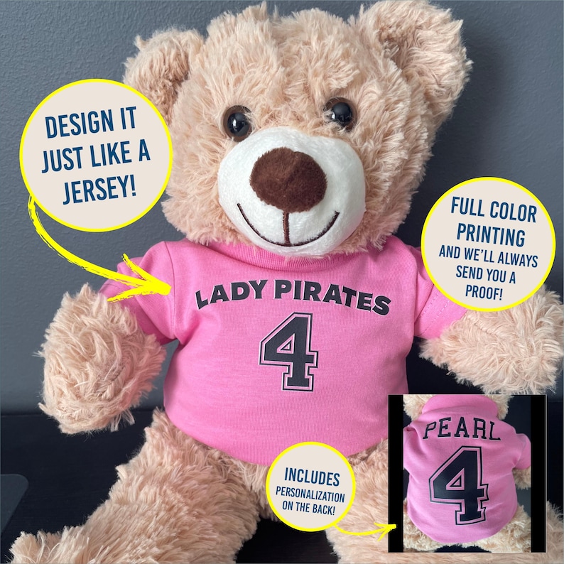 May include: A plush teddy bear wearing a pink t-shirt with the words "LADY PIRATES" and the number "4" printed on it. The shirt includes personalization on the back. The bear has a brown nose and is against a gray background.