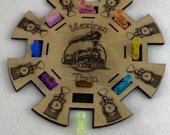 Può includere: Un tabellone di gioco in legno con un design a treno e le parole "Mexican Train". Il tabellone ha otto slot attorno al bordo, ognuno con un piccolo design di locomotiva. Ci sono nove pezzi di vagone di treno colorati, tra cui blu, viola, rosa, arancione, giallo e verde.