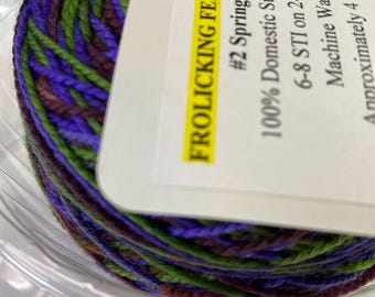 Può includere: Un gomitolo di filato colorato nei toni del viola, verde e marrone. L'etichetta recita "#2 Spring Meadow" e "100% Domestic Superwash Merino". L'etichetta indica anche che il filato è di circa 113 grammi e 439 metri.