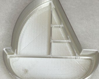 Può includere: Un piatto a forma di barca a vela stampato in 3D in plastica bianca con più scomparti.