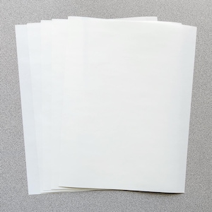 May include: A stack of multiple rectangular sheets of white paper. The paper has a smooth, opaque surface and is arranged in a slightly fanned-out pile, showing the clean, straight edges of each individual sheet stacked together.
