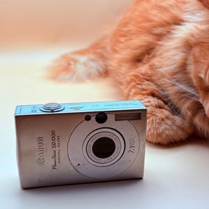 May include: A white ceramic mug with a black handle and the text "But First, Coffee" in a bold, black font. The mug sits on a white surface, showcasing its clean design.
