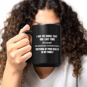 May include: Black ceramic mug with a white text that reads "I DID THE DANIEL FAST ONE LAST TIME because I'M BREAKING GENERATIONAL PATTERNS OF POOR HEALTH IN MY FAMILY". The mug has a black handle.