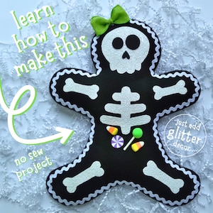 May include: A black felt gingerbread-style skeleton figure with a silver glitter skull, ribcage, and bone accents. It features a lime green bow at the top, candy embellishments, and white rickrack trim. Text reads: learn how to make this, no sew project, just add glitter decor.