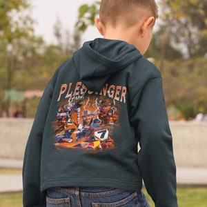May include: A dark green hooded sweatshirt with a colorful graphic print of a race car and the text "Pleschinger" on the back. The sweatshirt has a zipper and a hood.