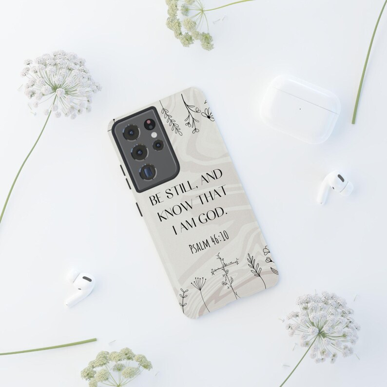 K&ouml;nnte beinhalten: Eine Handyh&uuml;lle mit beigefarbenem Hintergrund und einem schwarz-wei&szlig;en Blumendesign. Der Text "Be still, and know that I am God. Psalm 46:10" ist auf der H&uuml;lle aufgedruckt.