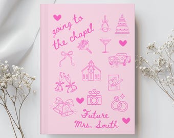 May include: Pink notebook with the text "going to the chapel" and illustrations of wedding-related items, including a church, a wedding cake, a champagne flute, a bouquet of flowers, a car, a camera, wedding rings, and bells. The text "Future Mrs. Smith" is at the bottom of the notebook.