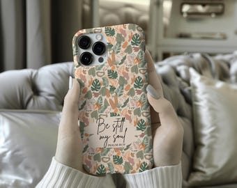 May include: A phone case with a botanical pattern of green, orange, and brown leaves on a cream background. The case has the text "Be still my soul" and "Psalm 46:10".