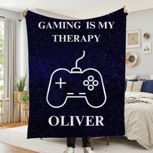 May include: A blue fleece blanket with a white gaming controller and the text "Gaming is my therapy" and "Oliver".