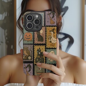May include: A phone case featuring a collage of Halloween-themed illustrations. The design includes a pumpkin, black cat, owl, haunted house, ghost, witch's hat, broom, and a cupcake with an eyeball. The case has a vintage postage stamp aesthetic.