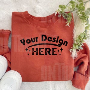 May include: A rust-colored sweatshirt with the text "Your Design HERE" in black with sparkling stars on either side of the text.