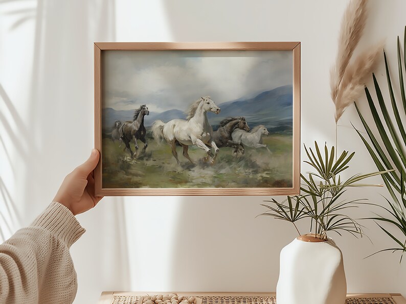 K&ouml;nnte beinhalten: Ein gerahmtes Gem&auml;lde von f&uuml;nf Pferden, die &uuml;ber ein Feld rennen. Die Pferde sind wei&szlig;, braun und grau, und das Feld ist gr&uuml;n mit einem blauen Himmel im Hintergrund.