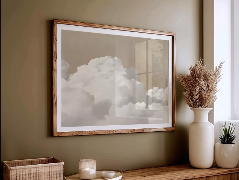 May include: A framed print of a cloudy sky with a window reflection. The frame is made of light brown wood and the print is in shades of gray and white.
