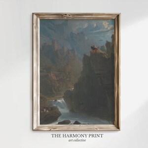 Peut inclure: Une impression d'art paysager encadrée représentant une chaîne de montagnes avec un château en pierre, une rivière et des falaises rocheuses. Le texte en bas indique THE HARMONY PRINT art collective. Le cadre est en bois clair.