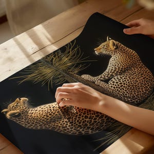May include: A black background with two leopards printed on it. The leopards are in a golden color and are facing different directions. The leopards are surrounded by a golden colored plant.