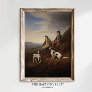 May include: A framed vintage painting depicts two men and two dogs on a hillside. The men are dressed in period attire, and the dogs are white with brown spots. The background shows a landscape with a cloudy sky. The frame is a light brown color.