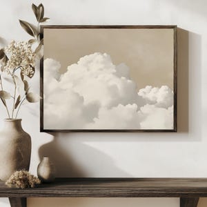 May include: A framed print of a beige and white cloudy sky. The print is hanging on a white wall above a wooden shelf with a brown vase and a small brown vase.