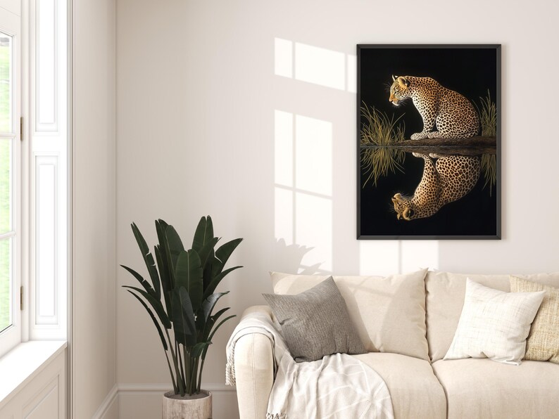 May include: A framed print of a leopard sitting in a body of water, looking at its reflection. The leopard is brown and black with spots. The water is dark and the background is black.