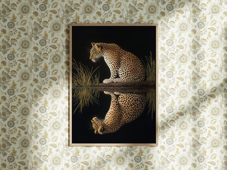 May include: A framed print of a leopard sitting by a body of water, with its reflection visible in the water. The leopard is brown and black with spots. The background is black.